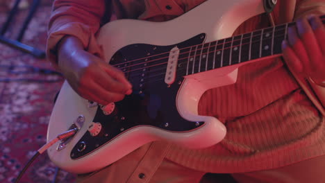 cerca de un músico irreconocible tocando la guitarra eléctrica en el estudio de grabación.