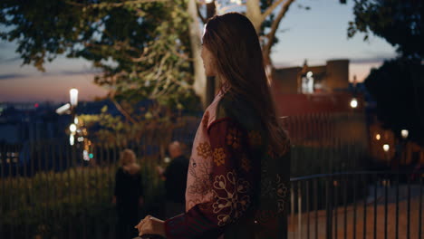 woman traveler standing railings looking on twilight city close up. happy girl