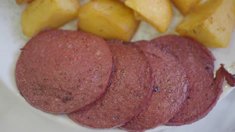 fried sausage slices and potatoes on a plate