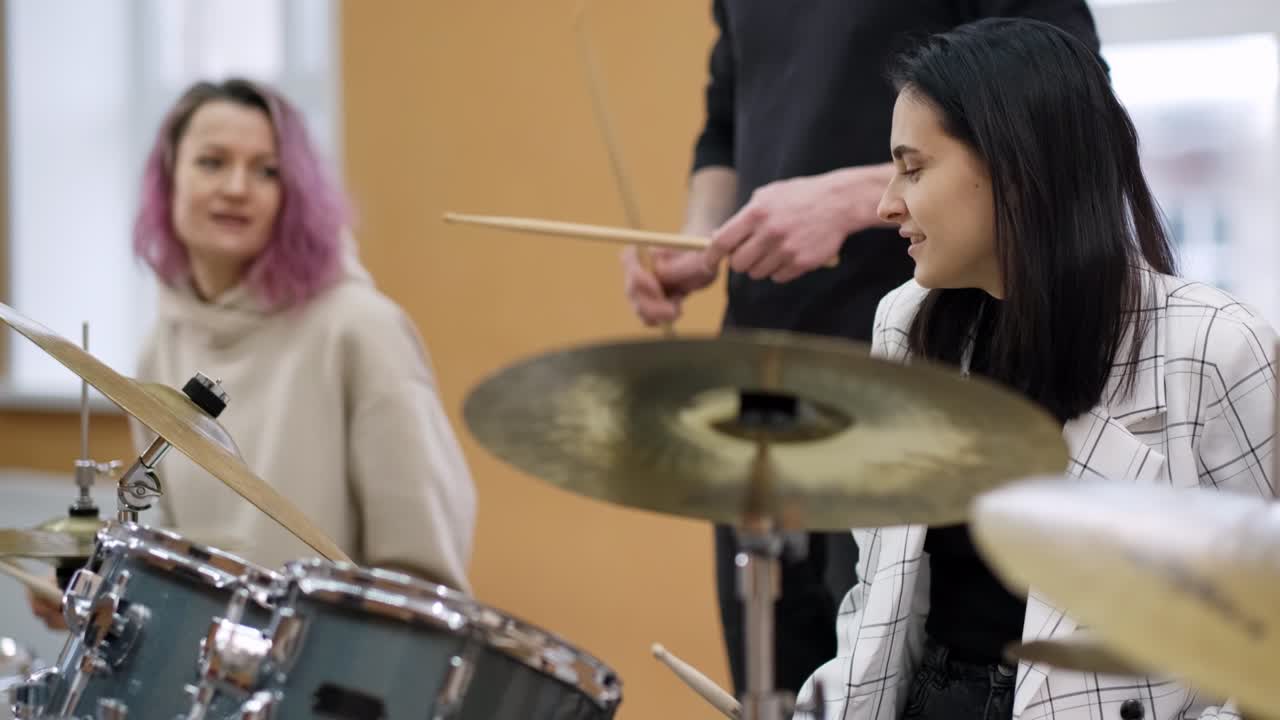 성인 젊은 남녀들은 학교에서 드럼을 연주하는 법을 배니다.