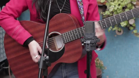 close up of brunette woman playing guitar outdoors in stage at city