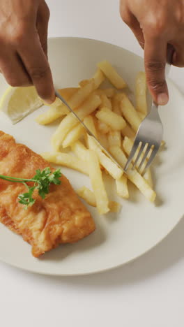 video overhead shot of african american hands eating fish and chips on white plate with copy space