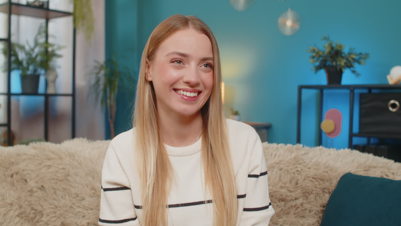 Caucasian woman paying purchase on sofa with mobile phone credit card smiling successful indoors