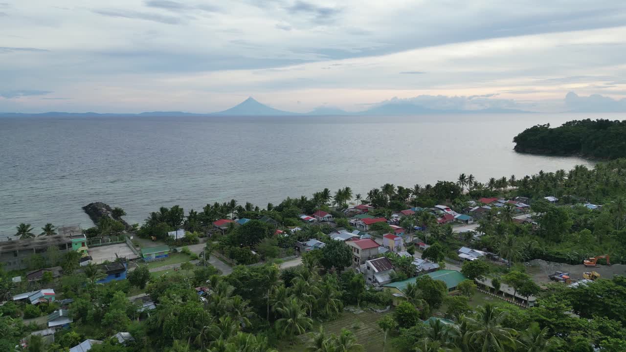 vista aérea de la ciudad rural frente a la playa con la silueta del volcán mayon que se avecina en el fondo