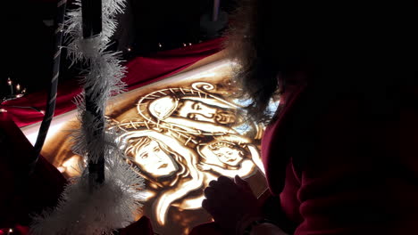 sand artwork drawing on lightning transparent glass surface, holy jesus christmas story