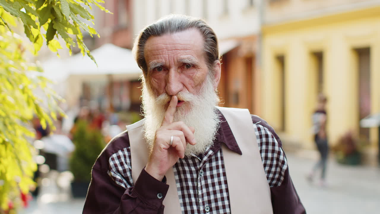 Senior man presses finger to lips makes silence hush sign do not tells gossip secret quiet in city