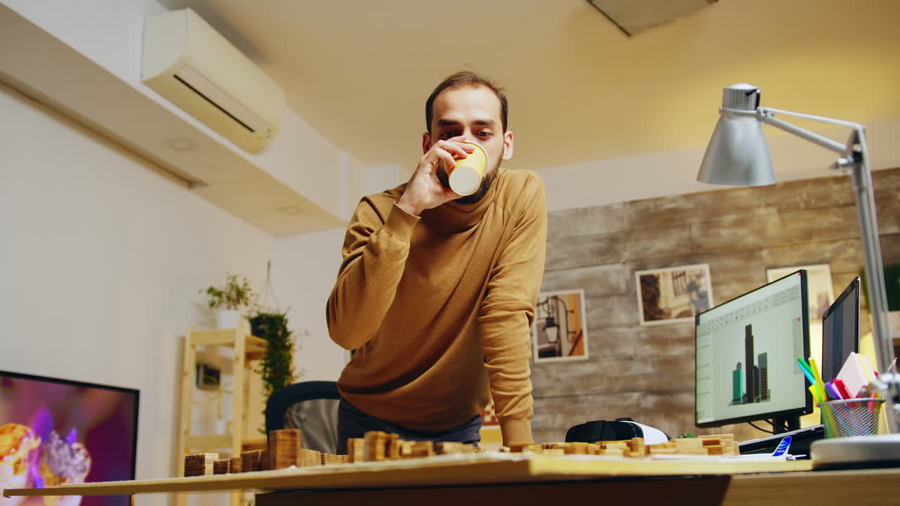 Tired architect taking a sip of coffee while working on a building project