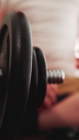 cute little boy plays with professional workout equipment in gym. toddler spins gear on heavy barbell sitting on wooden floor closeup slow motion