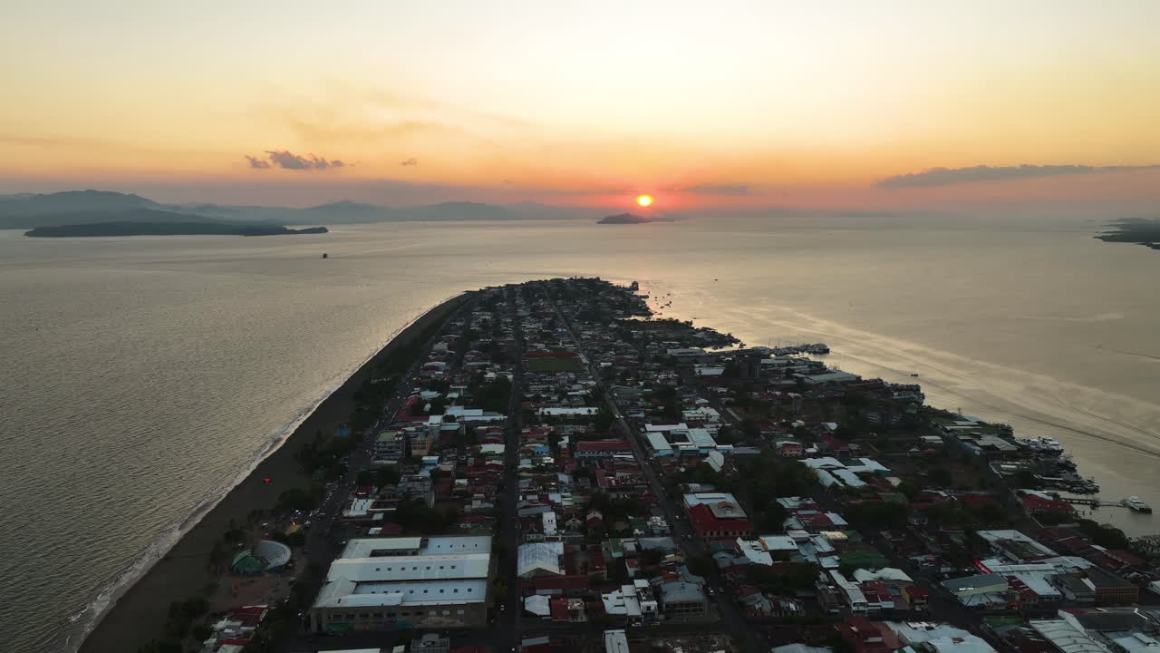 seguimiento aéreo filmado sobre la ciudad de puntarenas, colorido atardecer en costa rica