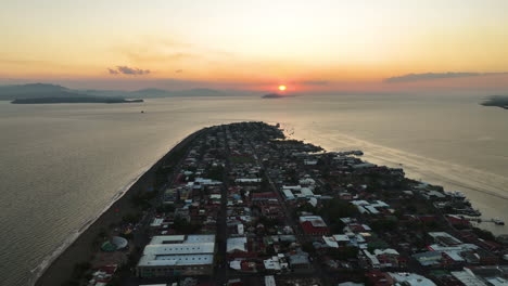 aerial tracking shot over the puntarenas city, colorful sunset in costa rica