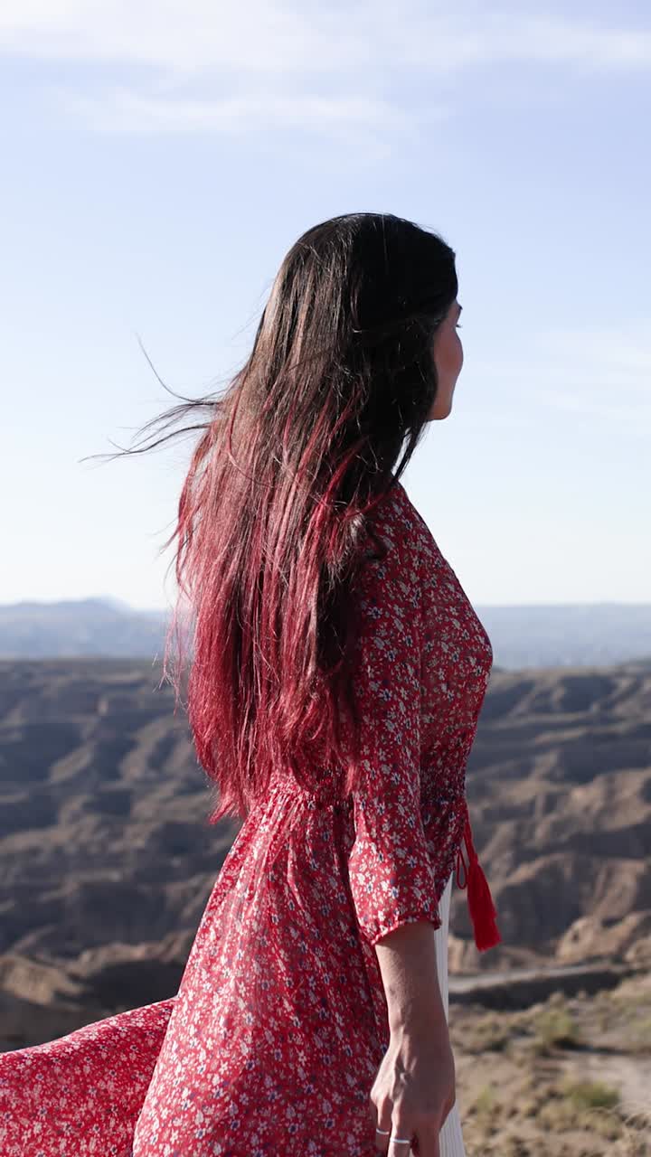 Una donna con un abito floreale rosso si gode il paesaggio desertico ventoso