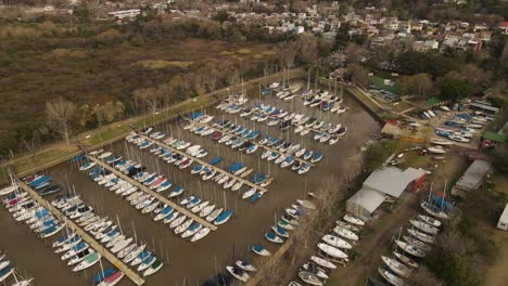 aerial view of a harbor with many sailing boats anchored on a wooden pier near an urban area