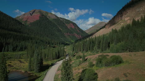 aerial drone cinematic ice lake basin trailhead dirt county road summer early morning silverton telluride colorado rocky mountains aspen forest 14er peaks forward motion