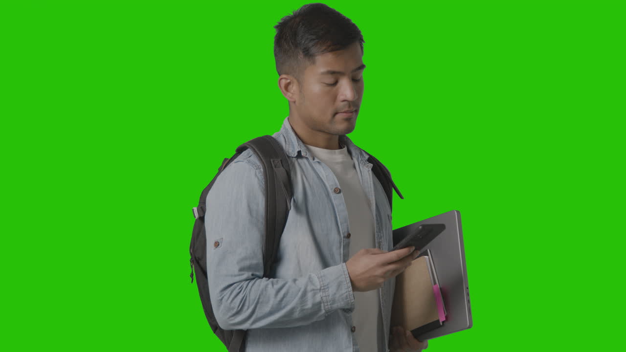 ritratto di studente universitario o universitario maschile sorridente che guarda il cellulare sullo schermo verde 1