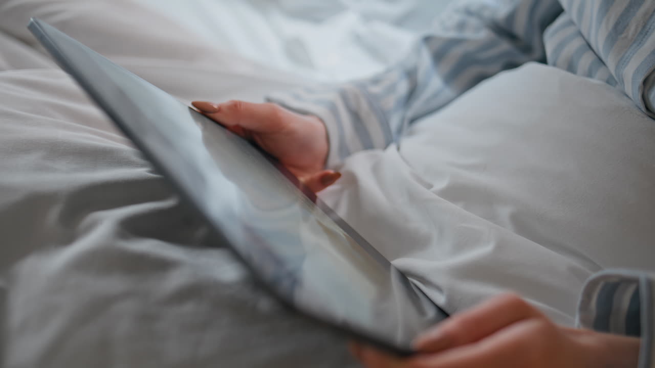 Girl hands holding tablet in morning bed closeup. Unknown woman watching seminar