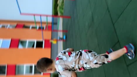 sweet caucasian kid wearing suit with mickey mouse stands outdoors. happy active child runs away, turns and climbs to a slide. vertical screen.