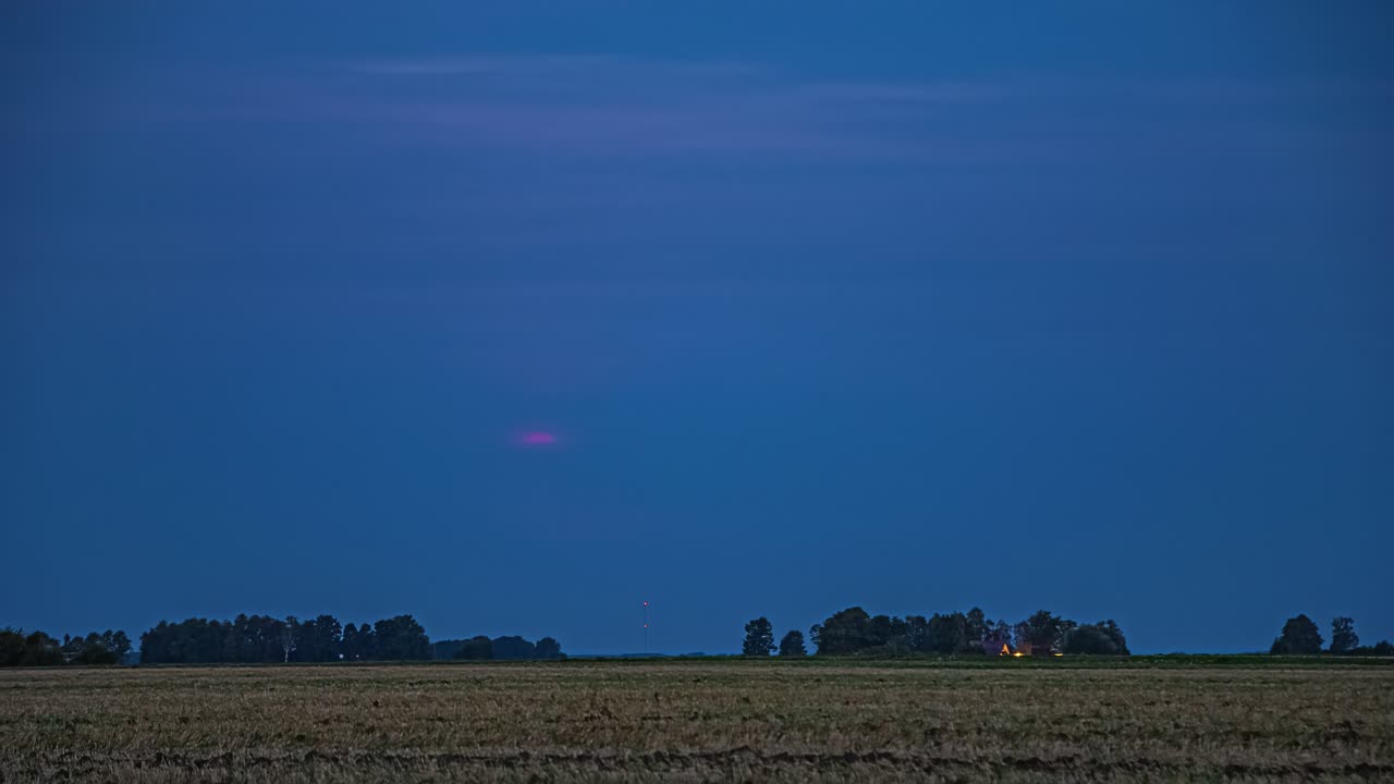 Aikaviivekuvaus kirkkaan kultaisen auringonlaskun pimentyessä yöksi.