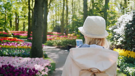 woman with smartphone strolls through tulip garden