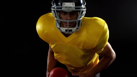 american football player holding ball against black background 4k