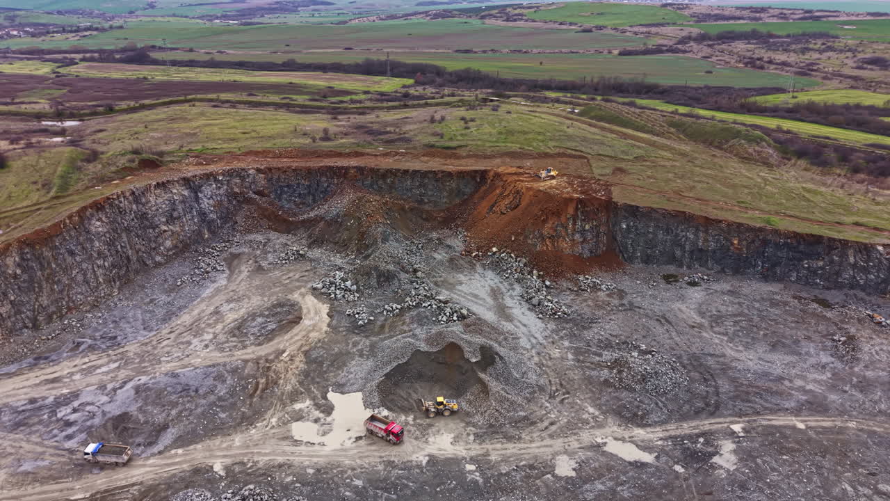 Granite quarry operation in rural area with heavy machinery and exposed rock formations at work site under clear sky