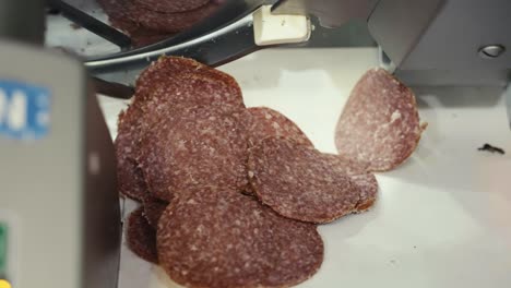 Close-up-of-a-meat-slicer-cutting-thin-slices-of-salami