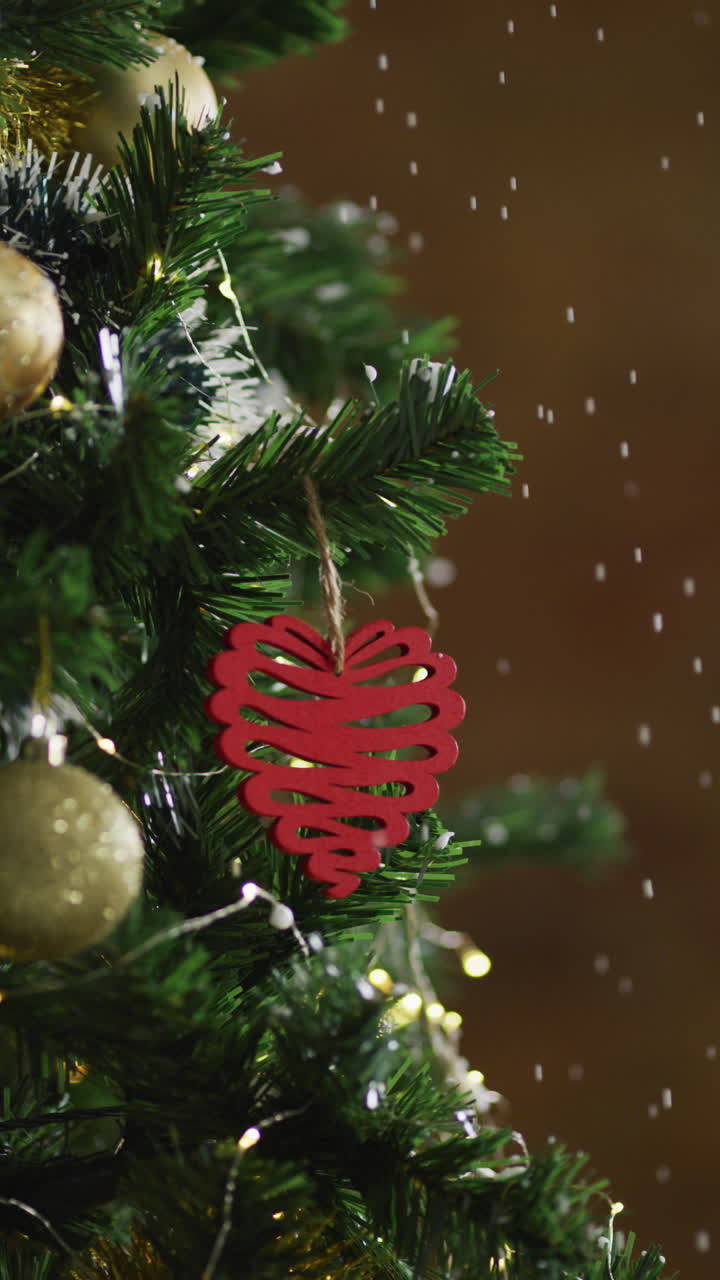 ornamento de corazón rojo en el árbol de navidad nevado capturado de cerca.