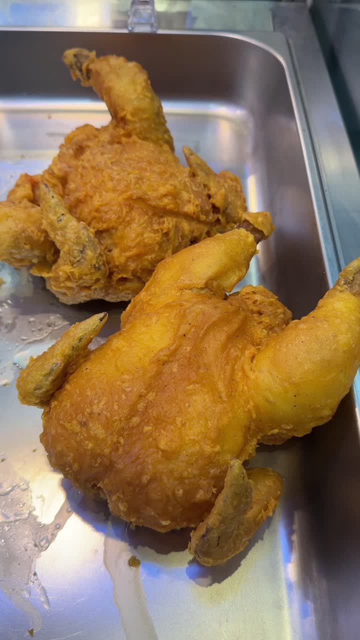 Due polli interi fritti dorati in un vassoio di metallo.