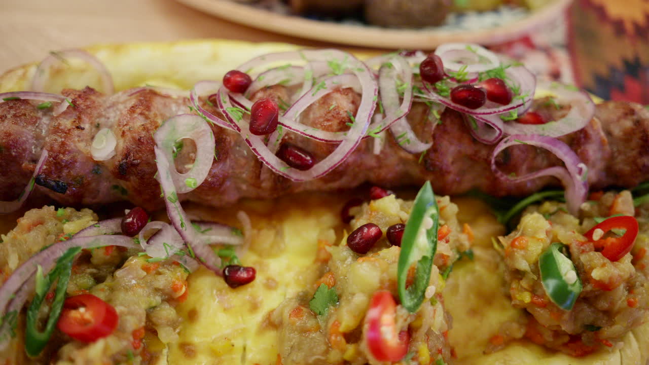 Carne picada a la parrilla servida sobre pan plano con verduras y hierbas