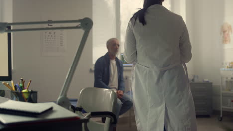 doctor taking tonometer stethoscope to measure pressure patient sitting hospital