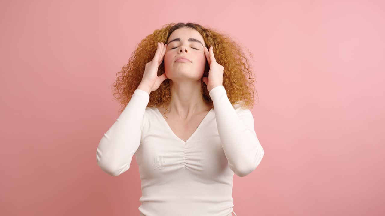 Young woman suffering from headache on pink background
