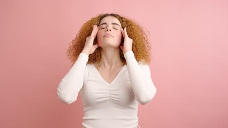 young woman suffering from headache on pink background