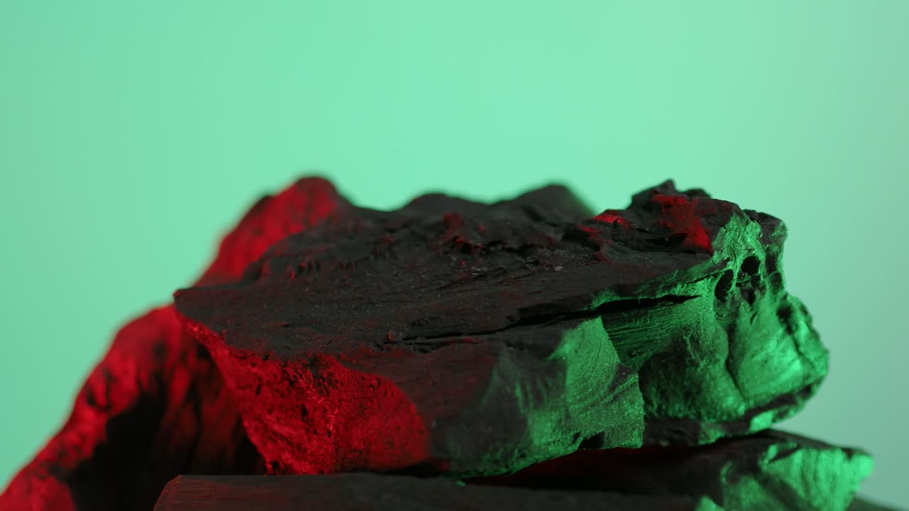 carbón de madera. madera natural o carbón negro tradicional en bucle en giratorio. fondo de pantalla azul o verde con luz led de color. disparo en estática. carbón para cocinar en la parrilla de la barbacoa. carbón negro.