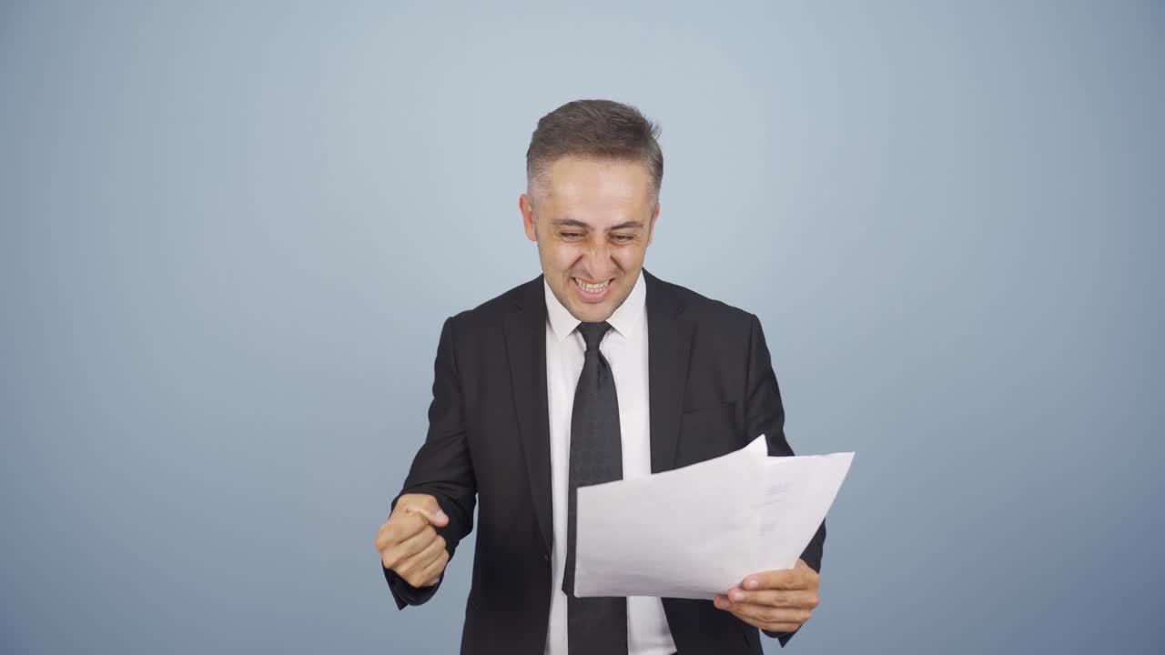 el hombre de negocios mira el documento en su mano y se alegra.