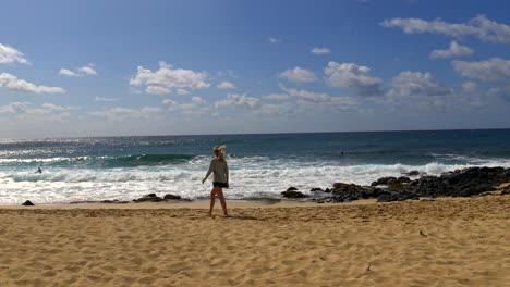 Young-blonde-woman-walks-to-sea-at-Shipwreck-Beach-south-shore-of-Kauai,-Hawaii-in-the-beautiful-Pacific-Ocean,-4k