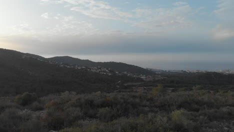 Sideways-drone-track-reveals-hill-scape-during-sunset,-valley-and-bright-sky-contrast