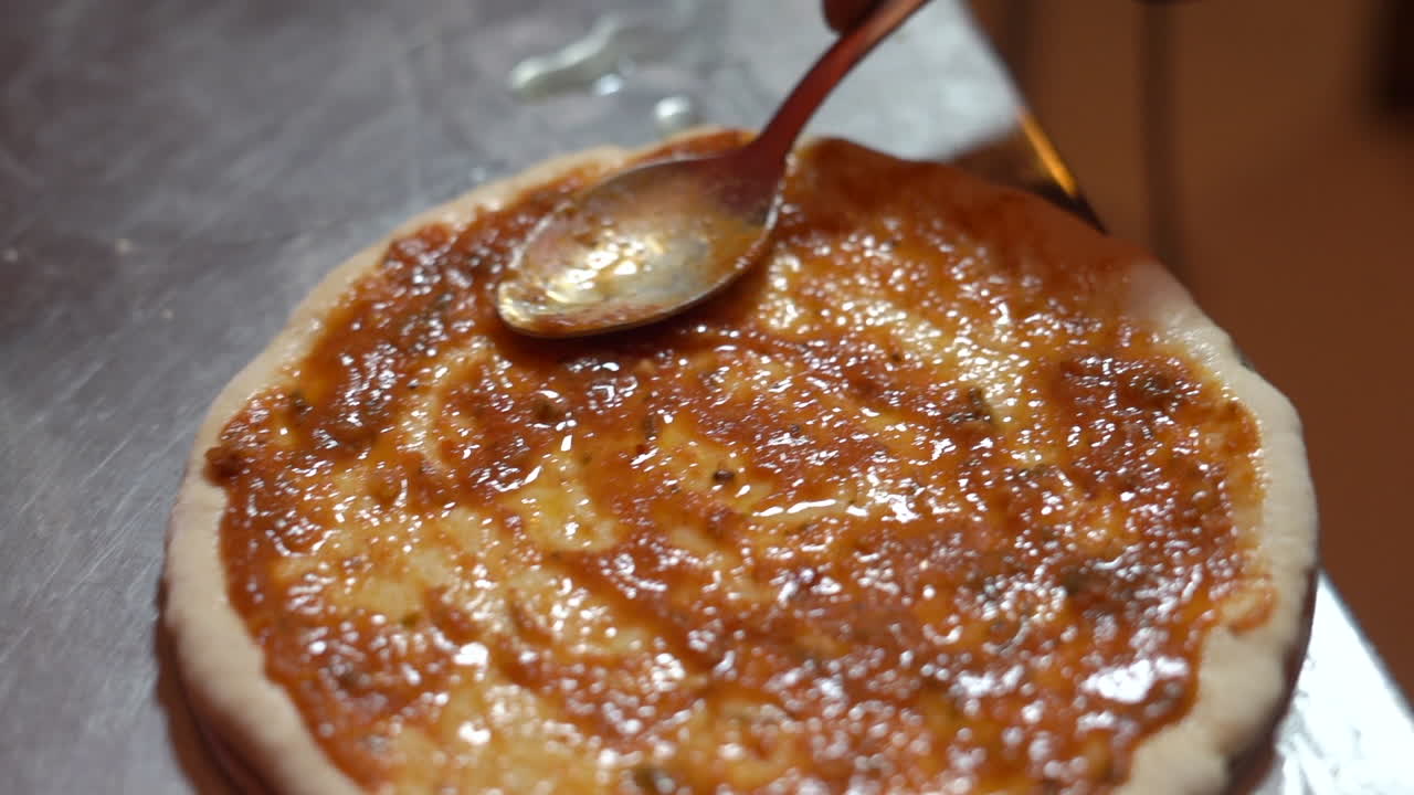 한 남자가 피자를 만들기 위해 피자 반죽에 수스를 추가합니다.