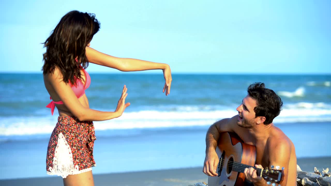 백인 남성이 기타를 연주하고 히스패닉 여성이 춤을 춘다.