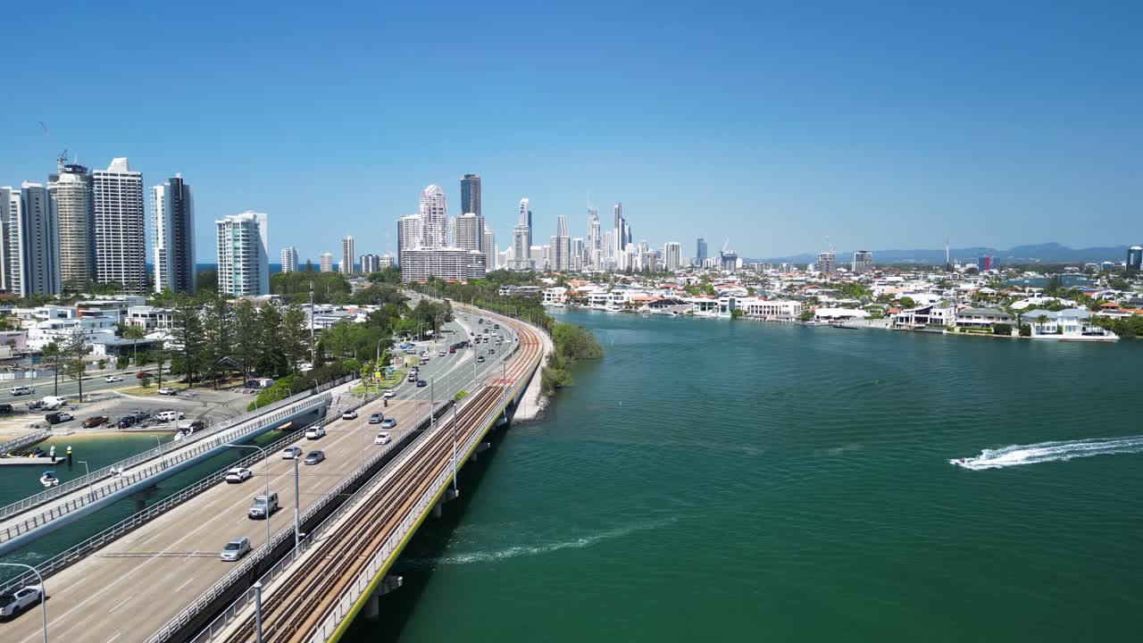 통근 교통은 해안 물체 위에 있는 다리를 가로질러 높은 도시 스카이라인으로 들어갑니다.