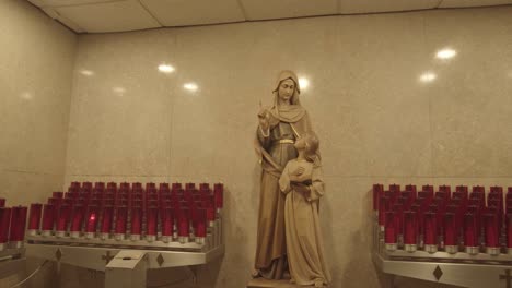 votive prayer candles surrounding a statue of the virgin mary