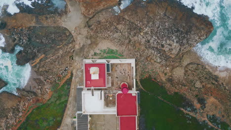 top view coastal lighthouse on ocean cliffs. beacon placed on rocky seashore