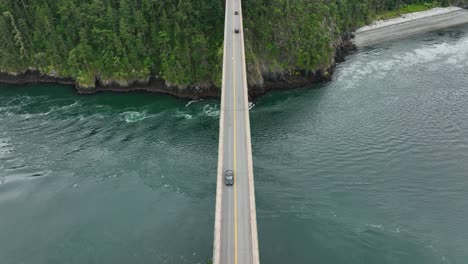 Drohnenaufnahme-Von-Oben-Nach-Unten,-Die-Ein-Auto-über-Eine-Brücke-über-Den-Ozean-Verfolgt