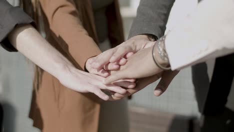 close-up shot of multiethnic employees putting hands together