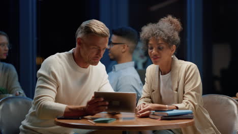 smiling colleagues discussing business plans on tablet