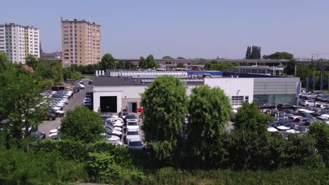 Toma-Aérea-Entre-Los-árboles-De-Un-Edificio-Comercial-Con-Un-Rascacielos-Al-Fondo