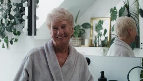 Portrait-of-cheerful-senior-woman-wearing-bathrobe