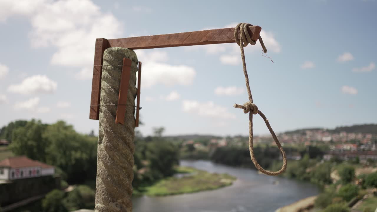 Weathered noose hangs from stone pillar above river in Barcelos Portugal