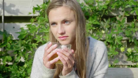 chica con ojos brillantes disfruta del té afuera bajo la cálida luz del sol, de cerca
