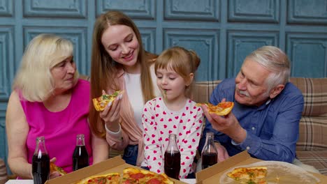 Mehrgenerationenfamilie-Mit-Mittagsparty,-Füttert-Mädchen-Mit-Pizza,-Lacht,-Genießt-Das-Essen