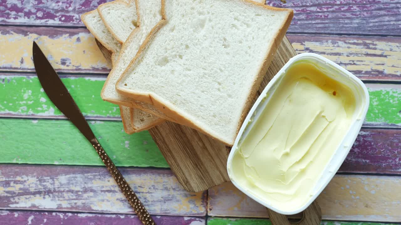 Fette di pane con burro su tagliere di legno