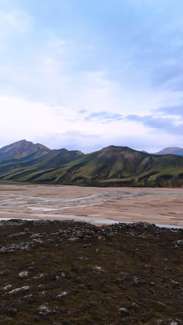 barren rocky landscape of iceland. mountains with no vegetation on and narrow river crossing the valley. vertical video.